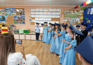 Dzieci sześcioletnie ustawione w szeregu na niebieskim tle